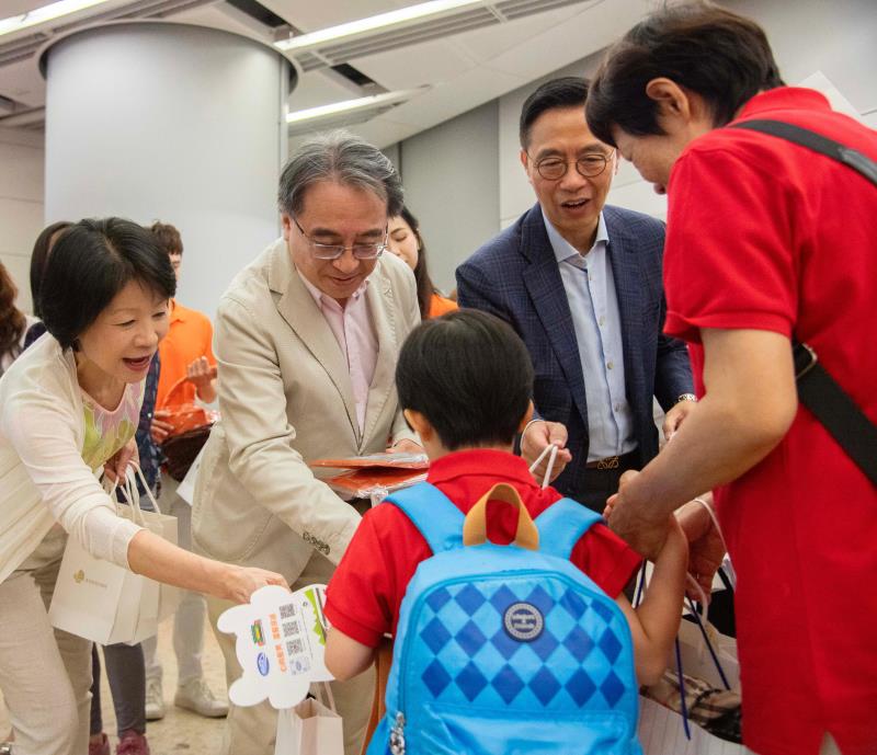 文化體育及旅遊局局長楊潤雄(右)及港鐵行政總裁金澤培(左二), 在西九龍站的大堂迎接旅客及派紀念品.