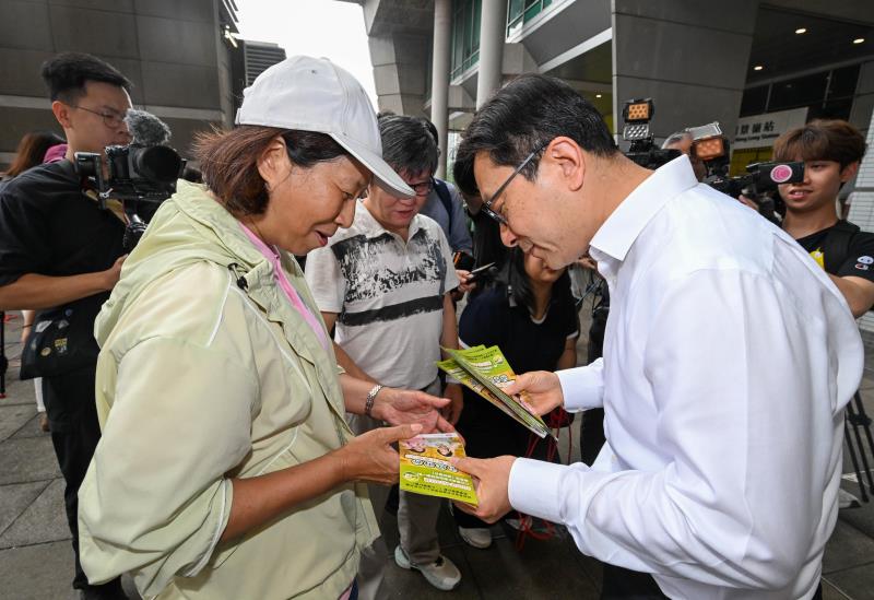 孫玉菡(右)視察「兩蚊兩折」推行狀況，並向受惠者派發宣傳單張。(政府新聞處圖片)