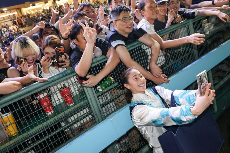 馬會周三夜馬放煙火賀煞科，騎師派公仔與眾同樂, 女騎師黃寶妮(前)應馬迷要求合照。(馬會圖片)