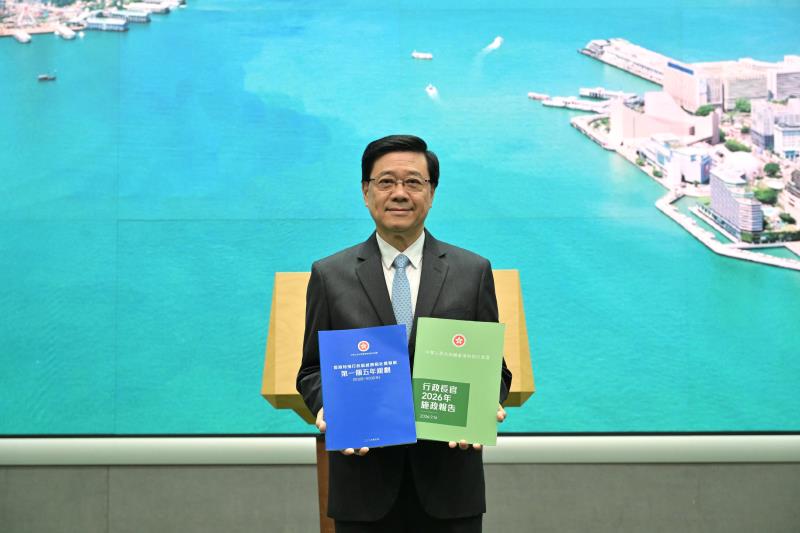 李家超展示將於明日發表的本港首份《五年規劃》及最新一份《施政報告》。政府新聞處提供。