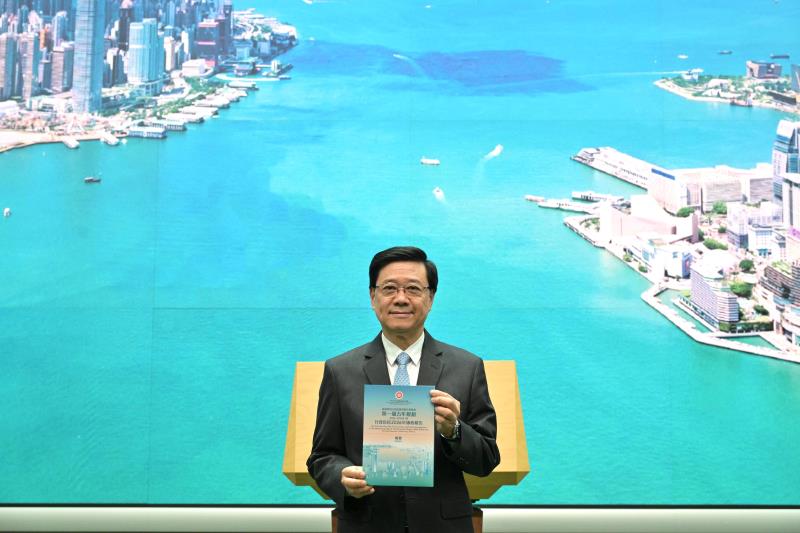 行政長官李家超展示兩份文件「一套兩策摘要」，以維港晨曦欣欣向榮的景象為封面，並融合「規劃」和「施政」兩份文件藍綠兩主色。 (政府新聞處圖片)