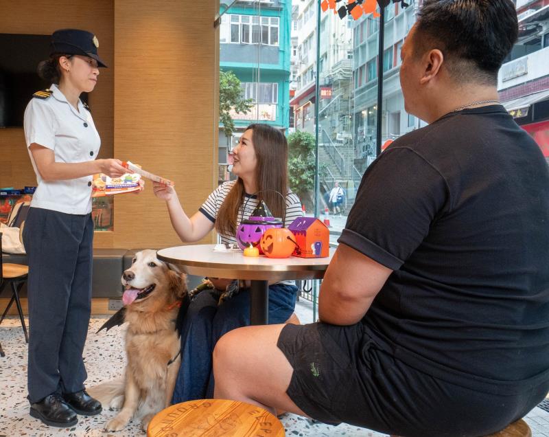 食環署人員到獲准食肆向攜狗顧客派發宣傳單張，提醒他們攜狗外出用膳時須守法依規。 (政府新聞處圖片)